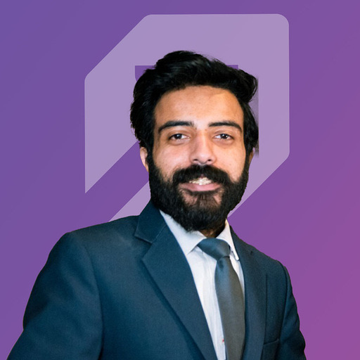 Danish Aziz Awan, smiling, in a dark suit and tie